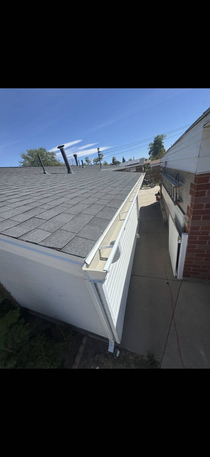 White seamless aluminum gutters newly installed along a brick rambler roofline