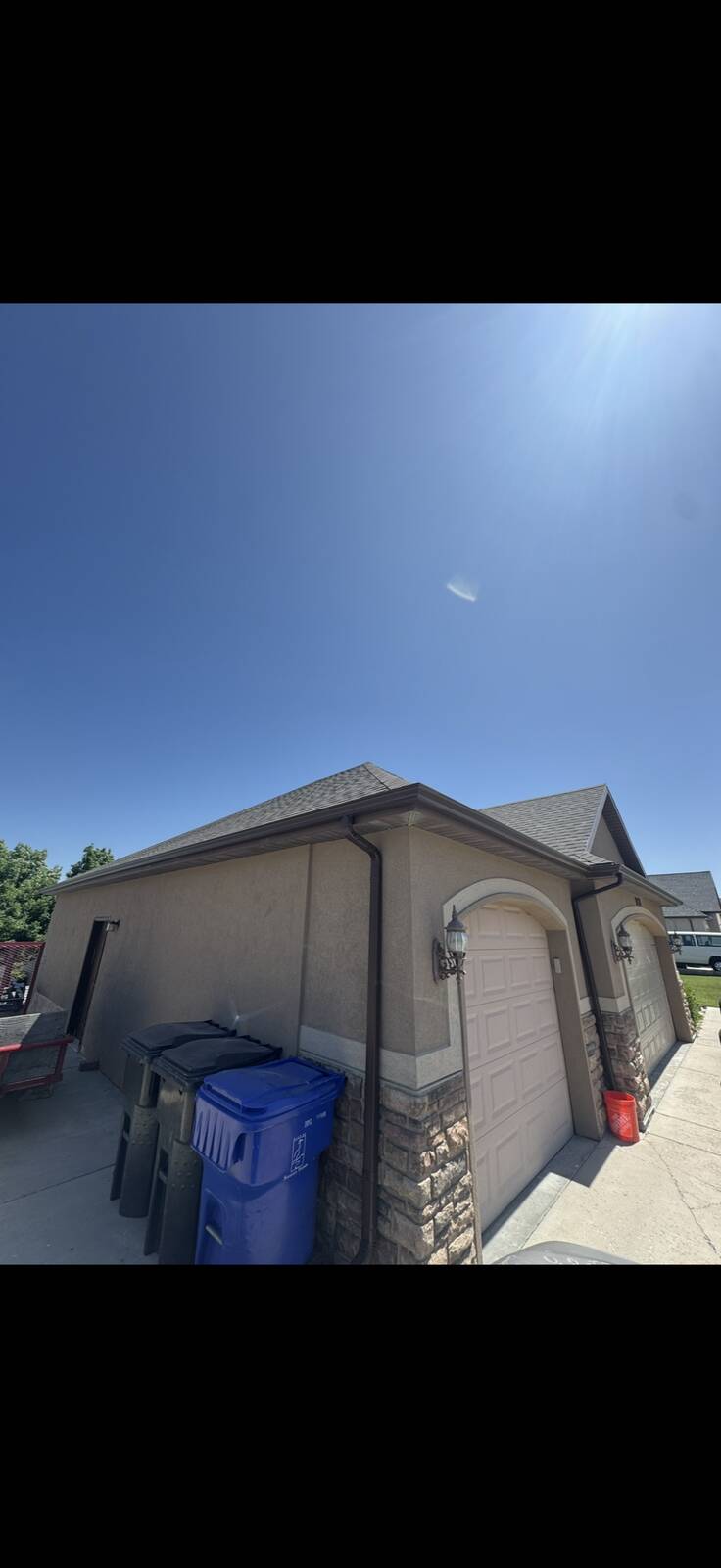 Bronze seamless gutters installed on a tan stucco ranch home with side-entry garage