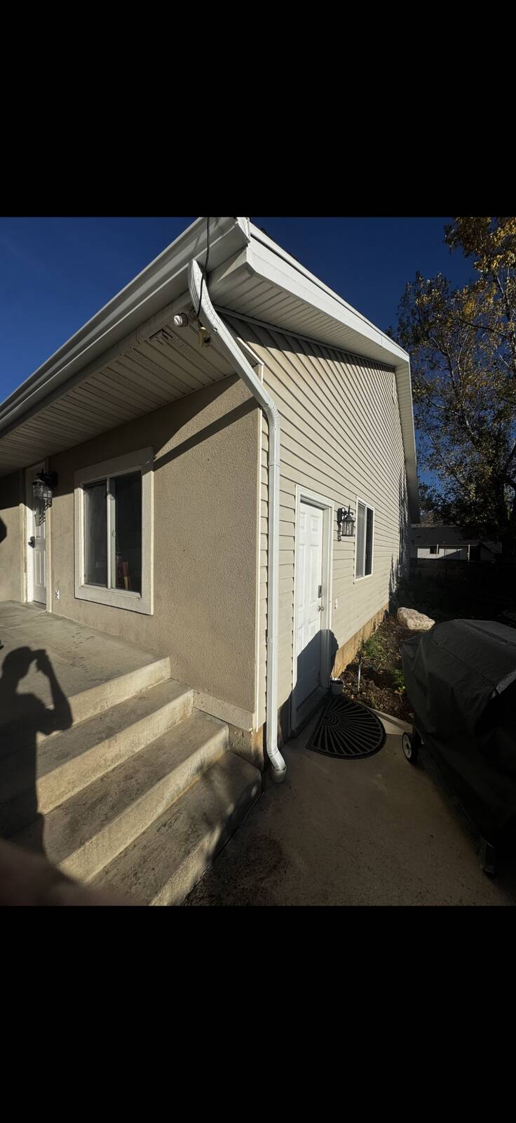 White seamless gutters installed at eave and corner of a beige stucco home
